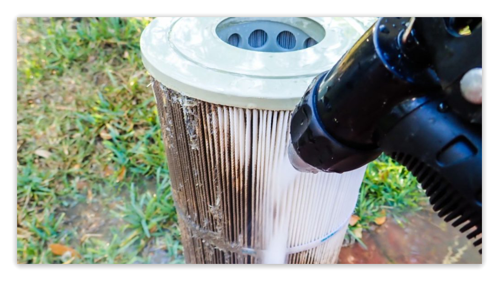 Close-up of a pool filter being cleaned with a hose, showing dirt being washed away.
