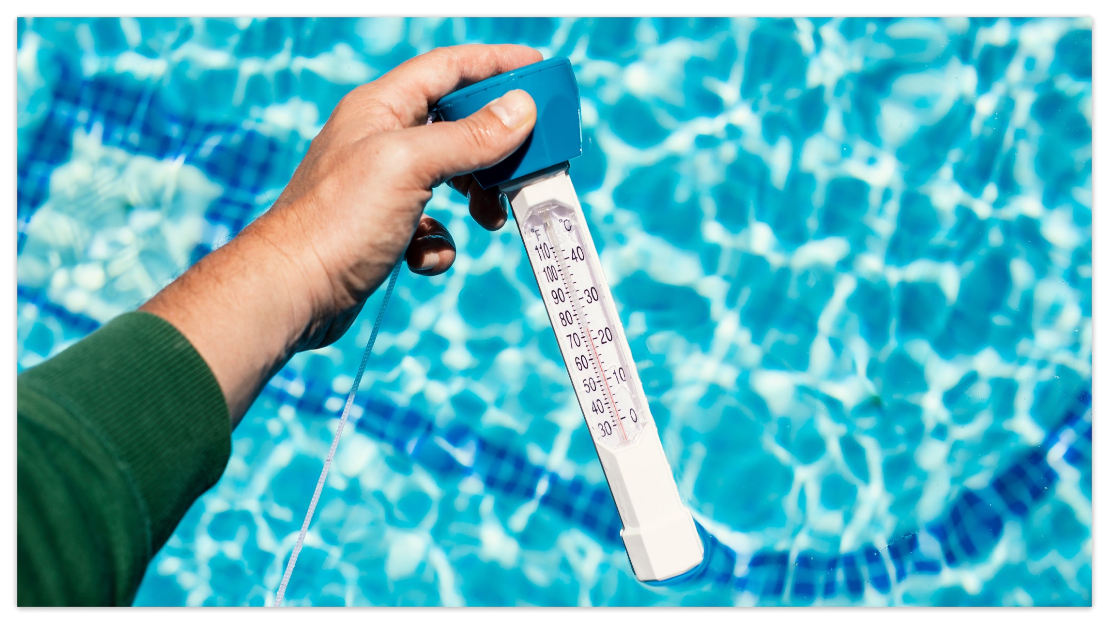 Hand holding a pool thermometer to check the optimal pool temperature for swimming safety and comfort.