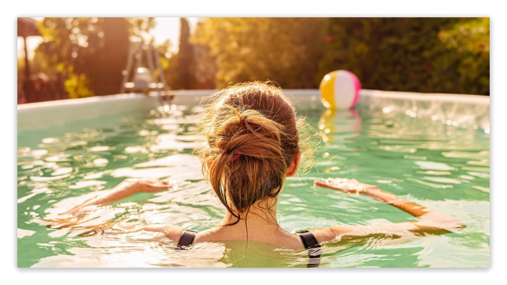 Person swimming in an above-ground pool with a beach ball in the background