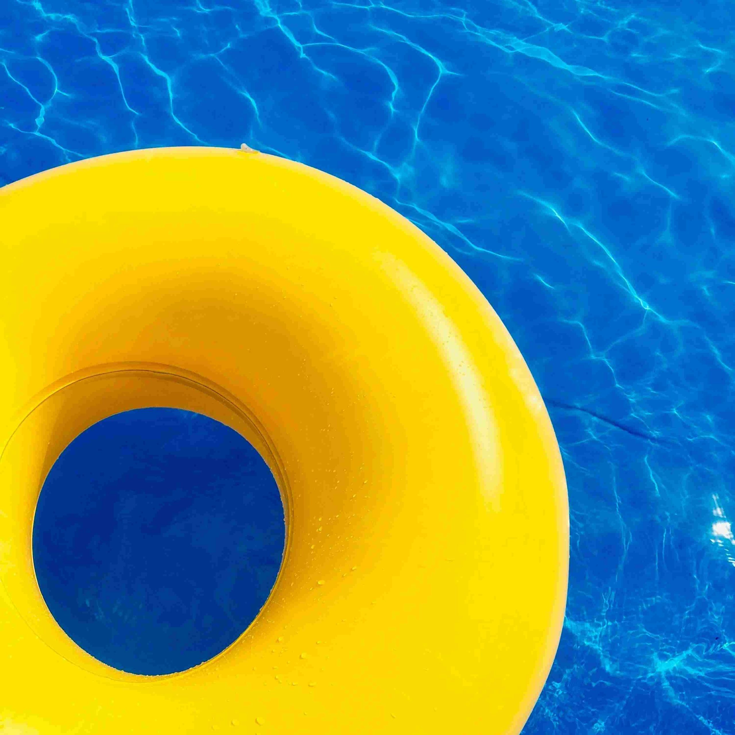 Yellow swimming ring on blue swimming pool water.
